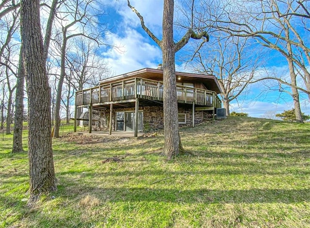 back of property with cooling unit, a deck, and a lawn