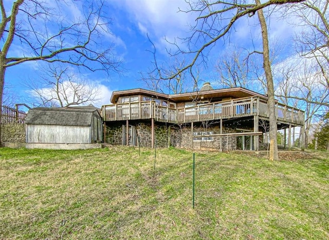 back of property with a yard, a wooden deck, and a shed