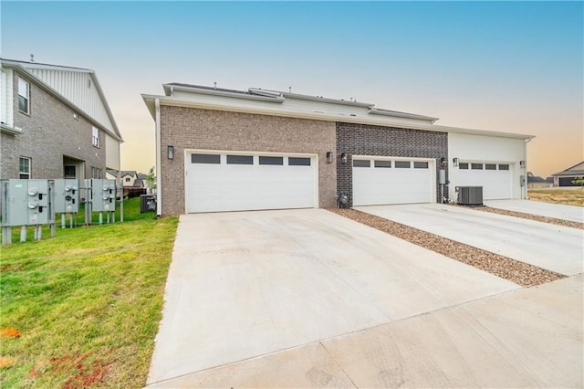 view of front of house featuring central AC unit, a lawn, and a garage