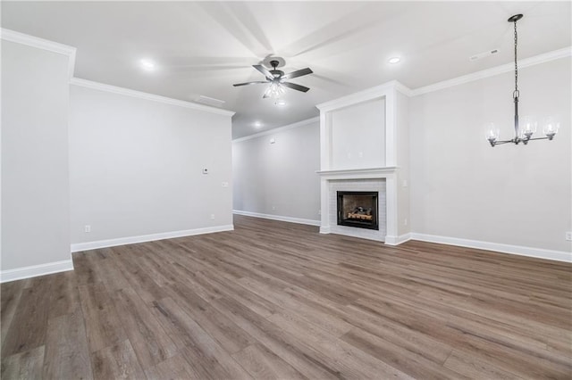 unfurnished living room featuring ceiling fan with notable chandelier, hardwood / wood-style flooring, and crown molding