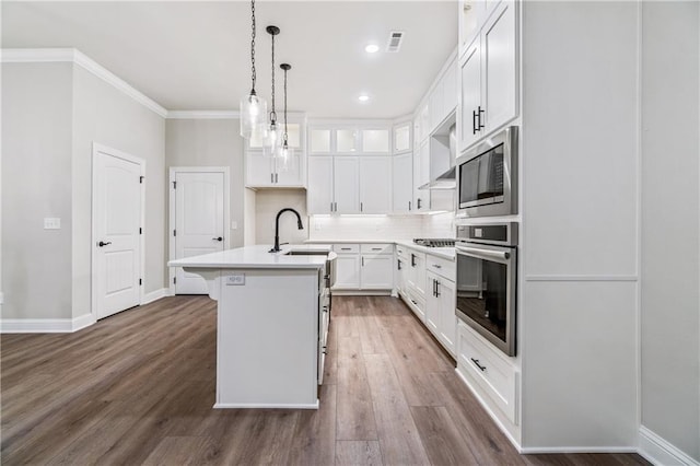 kitchen with stainless steel appliances, sink, white cabinetry, an island with sink, and dark hardwood / wood-style floors