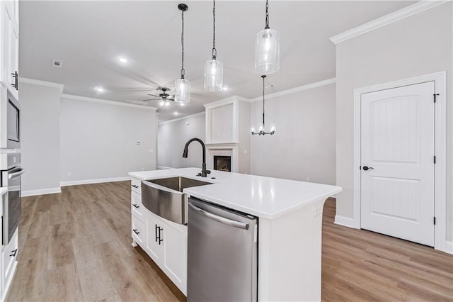 kitchen featuring a kitchen island with sink, stainless steel appliances, hanging light fixtures, sink, and white cabinetry