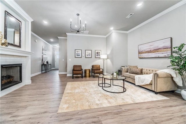 living room featuring a chandelier, hardwood / wood-style floors, crown molding, and a fireplace