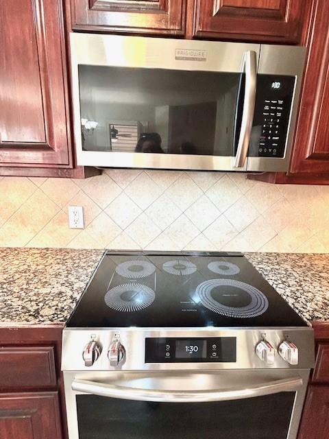 interior details with stainless steel appliances, light stone counters, and tasteful backsplash