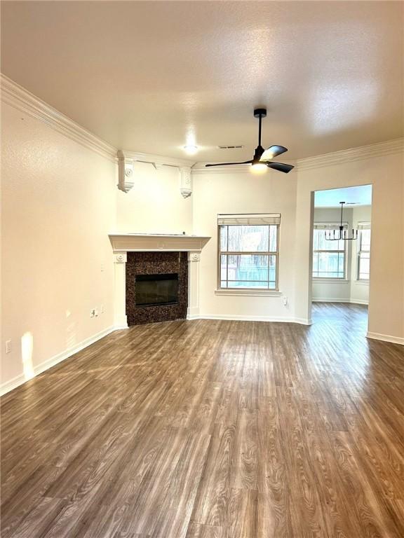 unfurnished living room with ceiling fan with notable chandelier, a high end fireplace, ornamental molding, and hardwood / wood-style flooring