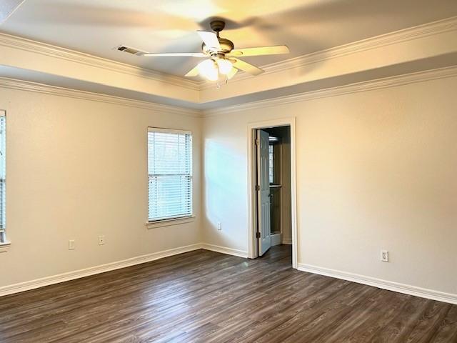 unfurnished room with ornamental molding, ceiling fan, dark wood-type flooring, and a tray ceiling