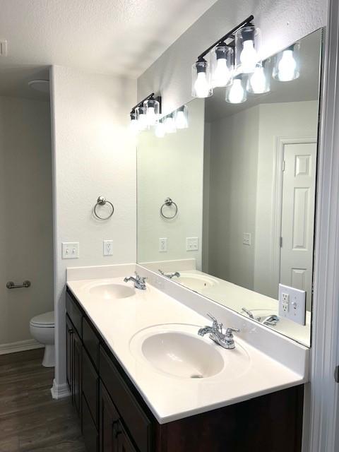 bathroom featuring toilet, a textured ceiling, hardwood / wood-style floors, and vanity