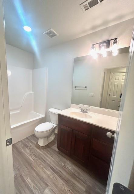 full bathroom with shower / bathing tub combination, toilet, vanity, and wood-type flooring