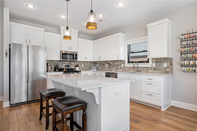 kitchen with a kitchen breakfast bar, stainless steel appliances, light countertops, and light wood-style floors