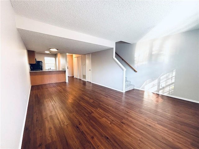 unfurnished living room with a textured ceiling and dark wood-type flooring