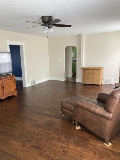 living room with dark hardwood / wood-style flooring, a textured ceiling, and ceiling fan