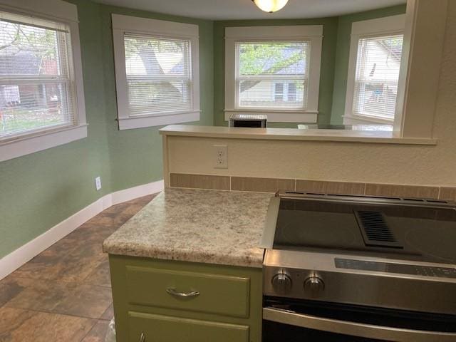 kitchen with green cabinets, stainless steel stove, and a healthy amount of sunlight