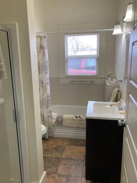 full bathroom featuring toilet, shower / bathtub combination with curtain, and vanity