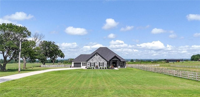 view of front of home with a garage, a rural view, and a front lawn