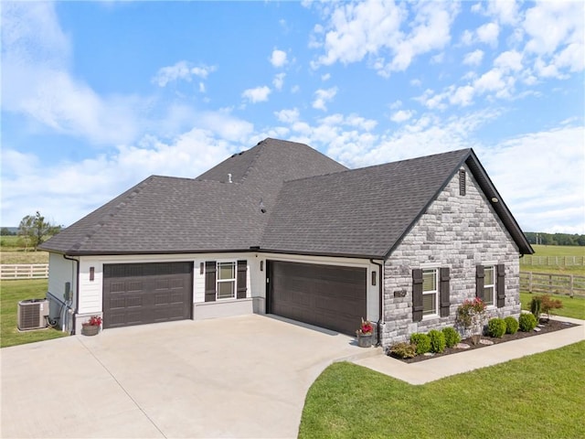 view of front of house featuring cooling unit, a front yard, and a garage