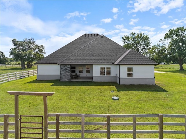 back of property with a rural view and a yard