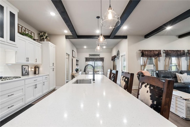 kitchen with white cabinets, beam ceiling, hanging light fixtures, and sink