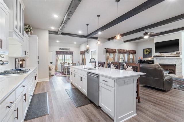 kitchen with appliances with stainless steel finishes, hanging light fixtures, an island with sink, a kitchen bar, and white cabinets