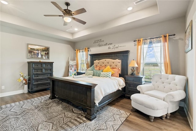 bedroom featuring wood-type flooring, ceiling fan, and a tray ceiling