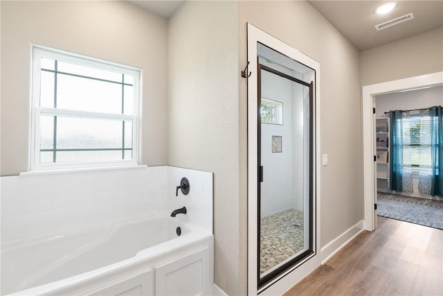 bathroom featuring independent shower and bath, hardwood / wood-style floors, and plenty of natural light