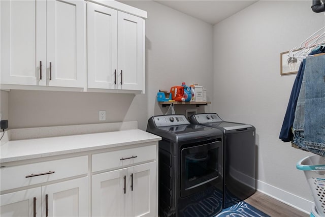 laundry area with hardwood / wood-style flooring, cabinets, and washing machine and clothes dryer