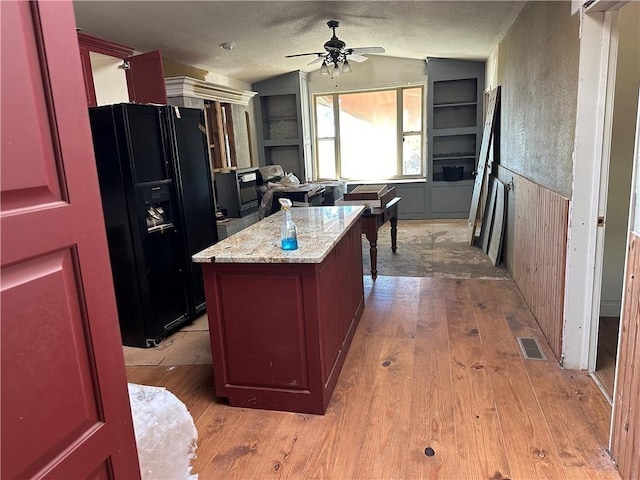 kitchen featuring black fridge, a kitchen island, lofted ceiling, built in features, and ceiling fan