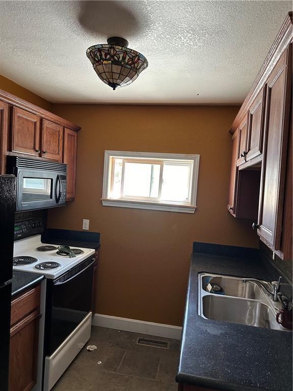 kitchen featuring sink, white electric range oven, and dark tile patterned floors