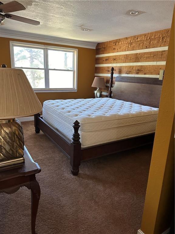 carpeted bedroom featuring a textured ceiling and ceiling fan