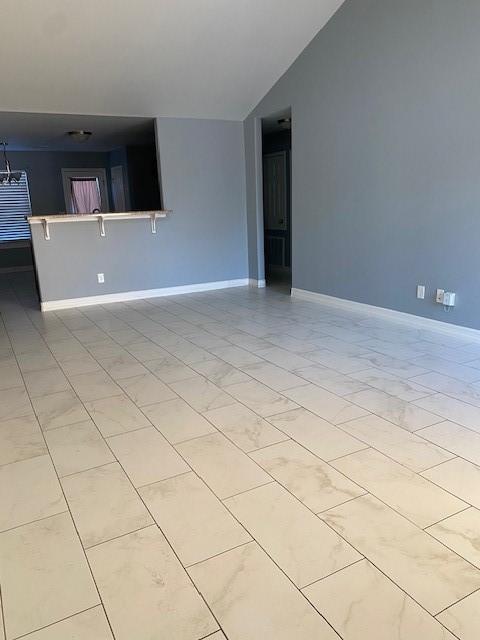 empty room featuring lofted ceiling and baseboards