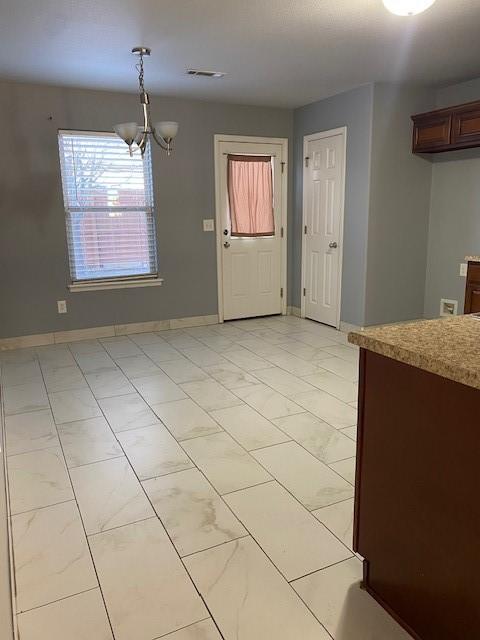 unfurnished dining area with baseboards, a chandelier, and visible vents