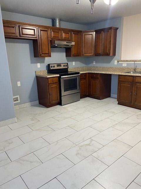 kitchen with under cabinet range hood, baseboards, stainless steel electric range oven, light stone counters, and a sink