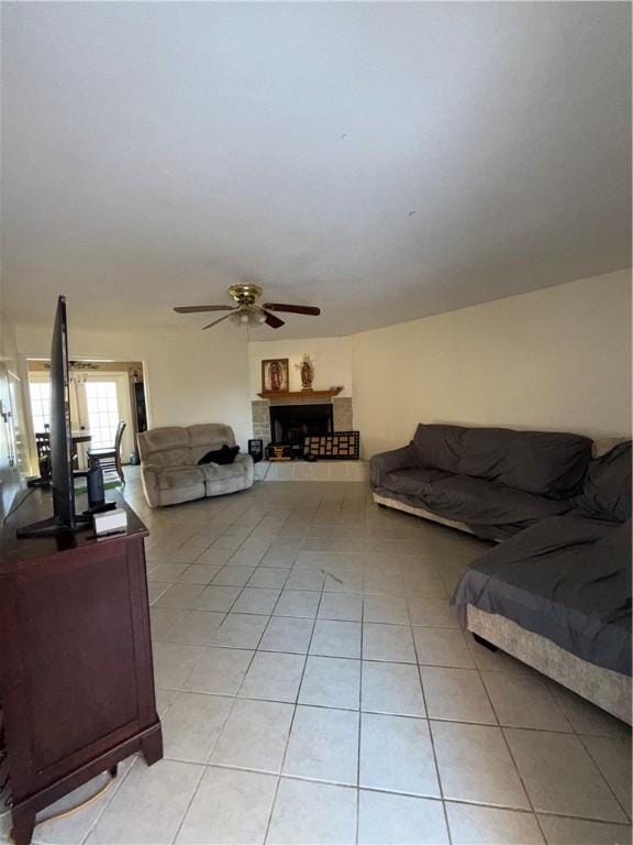 living room featuring a fireplace, ceiling fan, and light tile patterned floors