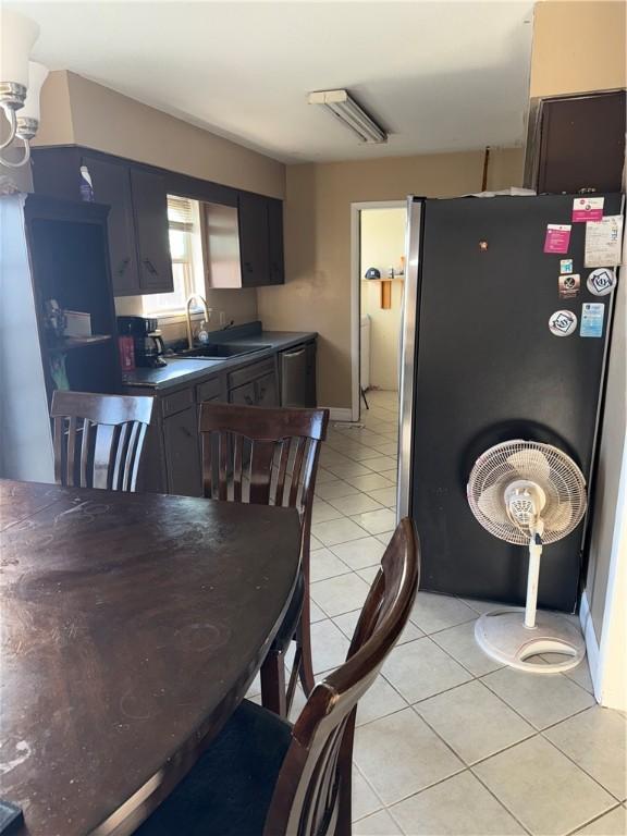 kitchen featuring sink, light tile patterned floors, and stainless steel fridge