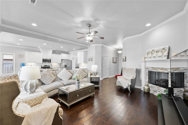 living room with ornamental molding, ceiling fan, a stone fireplace, and dark hardwood / wood-style floors