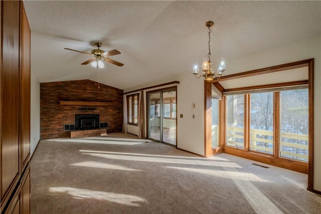 unfurnished living room with a textured ceiling, light colored carpet, a large fireplace, and ceiling fan with notable chandelier