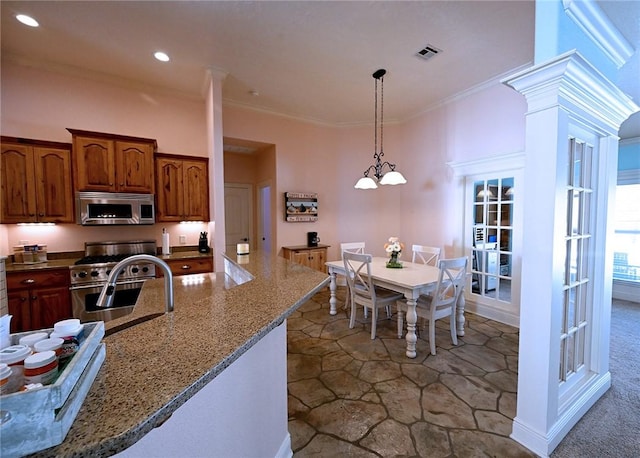 kitchen featuring stainless steel appliances, pendant lighting, crown molding, and light stone countertops