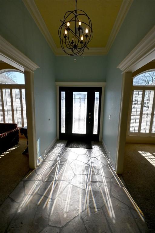 foyer featuring dark carpet, a chandelier, and plenty of natural light