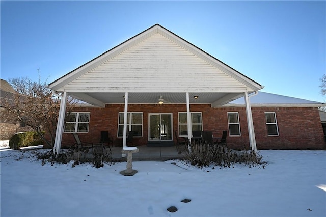 snow covered back of property featuring a porch