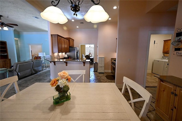 dining area featuring a textured ceiling, ceiling fan, crown molding, and independent washer and dryer