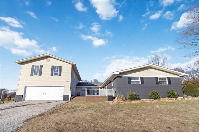 view of front of home featuring a garage, a front yard, gravel driveway, and a deck