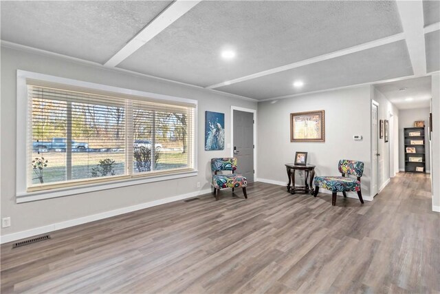 living area with coffered ceiling, a textured ceiling, hardwood / wood-style floors, and beam ceiling