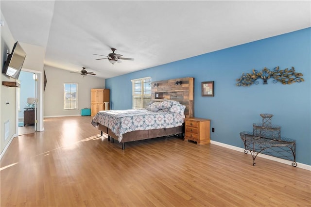 bedroom with multiple windows, ceiling fan, vaulted ceiling, and light wood-type flooring