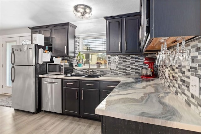 13693 N Mount Pleasant Rd, Gravette, AR 72736 - kitchen with stainless steel appliances, a sink, tasteful backsplash, and light wood-type flooring