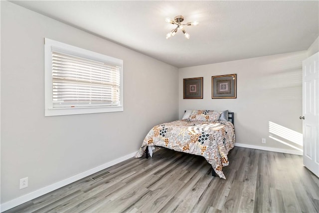 bedroom with visible vents, baseboards, and wood finished floors