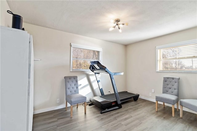 exercise room featuring light wood-type flooring and baseboards