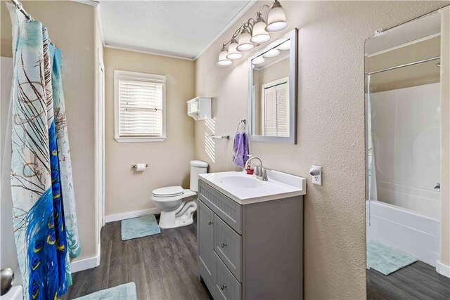 full bathroom featuring toilet, shower / bath combination with curtain, hardwood / wood-style floors, crown molding, and vanity