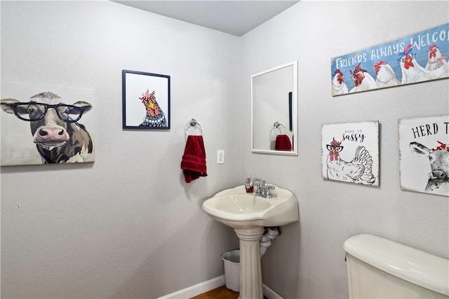 half bathroom with baseboards and toilet