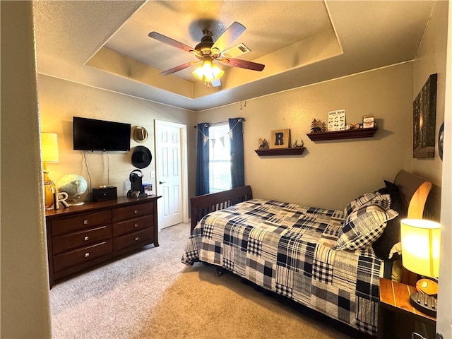 bedroom featuring a tray ceiling, a ceiling fan, carpet flooring, and a textured ceiling