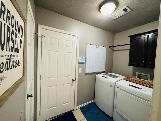 washroom with visible vents, washer and clothes dryer, a textured ceiling, cabinet space, and light tile patterned floors