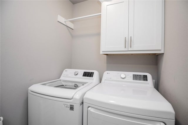 clothes washing area featuring washing machine and dryer and cabinets